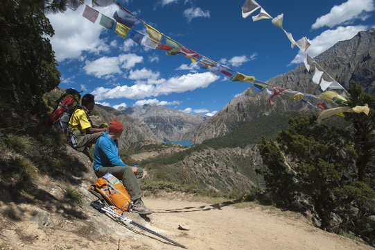 Prayer flags mark a high point in the trail where trekkers are rewarded with their first glimpse of Phoksundo Lake, Dolpa Region, Himalayas, Nepal