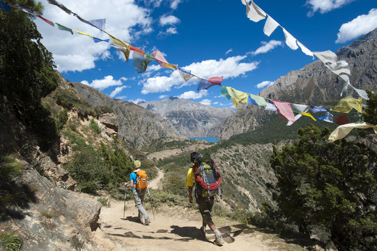 Prayer flags mark a high point in the trail where trekkers are rewarded with their first glimpse of Phoksundo Lake, Dolpa Region, Himalayas, Nepal