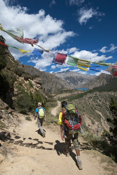 Prayer flags mark a high point in the trail where trekkers are rewarded with their first glimpse of Phoksundo Lake, Dolpa Region, Himalayas, Nepal