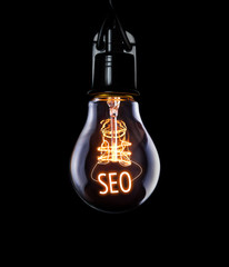 Hanging lightbulb with glowing SEO concept.
