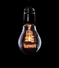 Hanging lightbulb with glowing Teamwork concept.