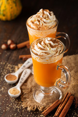 Pumpkin spice latte with whipped cream on top on rustic wooden background. Selective focus. Holiday autumn concept