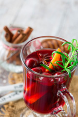 Christmas Hot mulled wine in glasses with orange slices, cranberry, anise and cinnamon sticks on white rustic wooden background
