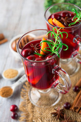 Christmas Hot mulled wine in glasses with orange slices, cranberry, anise and cinnamon sticks on white rustic wooden background, selective focus. Winter Holiday time concept
