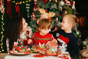 beautiful mommy and her cute childrens stands near Christmas coo