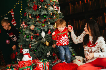 beautiful mommy and her cute doughter sitting near Christmas tre