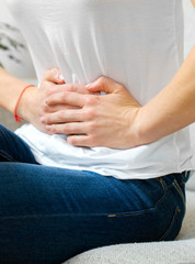 Unrecognizable woman on the bed with stomach pain.