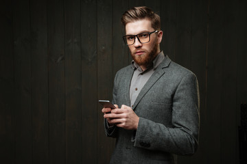 Man in casual suit and eyeglasses holding mobile phone