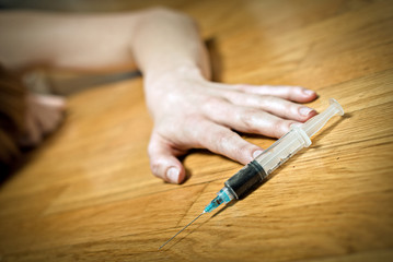 Syringe with heroin in front of drug addict female.