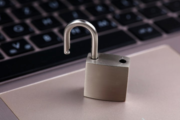 Padlock on silver aluminium notebook, laptop. Internet, web safety, privacy and security concept.
