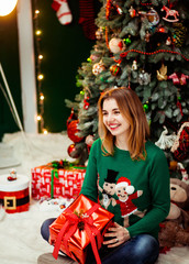 young and beautiful woman in cute green sweater holds gift box