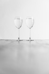 Two wine glasses filled with clear liquid on a wooden table