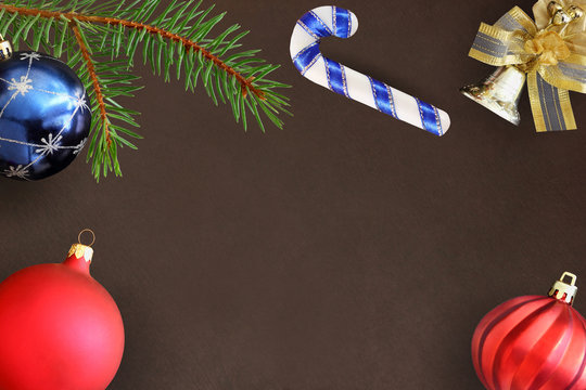 Christmas fir branch, stick, blue and red wavy dull balloon and decorative bell on dark background