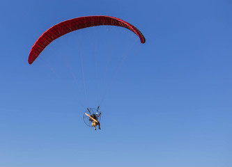 paraglider flying with paramotor on  blue sky  background
