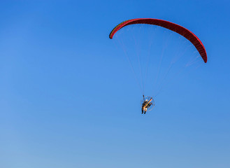 paraglider flying with paramotor on  blue sky  background