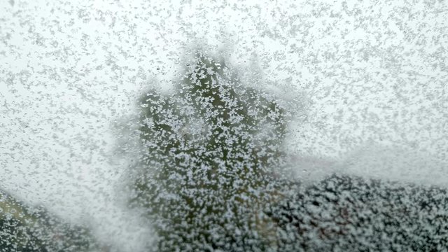 Close up footage of a car windshield, with snow falling on it.