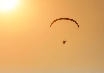 silhouette paraglider flying  with paramotor on sunset