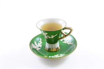 Side view of green and white teacup and saucer with tea, isolated on white
