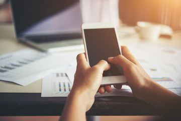 Business woman hands typing on mobile phone while working with h