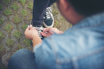 Hipster boyfriend tying shoes to his girls while go the relaxing