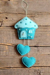 Felt house with hearts decor isolated on old wooden background. Handmade home wall decor. Felt wall decoration crafts for Christmas, Valentine's day, mother's day. Closeup. Top view