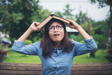 Young hipster woman cover her head with book, afraid of somethin