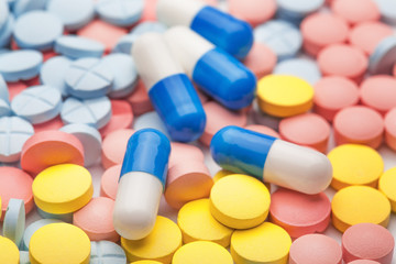 pile of medical pills in different colors and white-blue pills