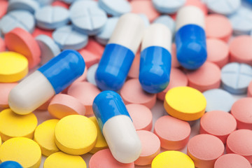 White and blue pills on a background of colored medical pills