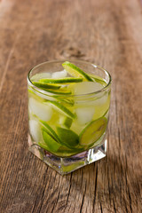 Cocktail Margarita with lemon and ice cubes in an old wooden table closeup