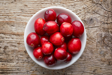 Bowl of cranberries on wooden table, from above