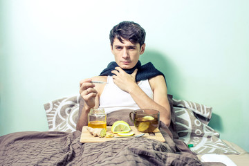 Fototapeta na wymiar young man lies in bed sick with colds and flu