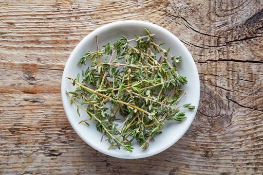 Bowl of thyme on wooden table, from above