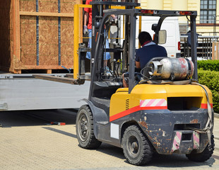 Forklift loads a truck on the street