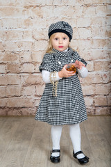 The child, a little girl holding a bottle of mother's perfume and beads.