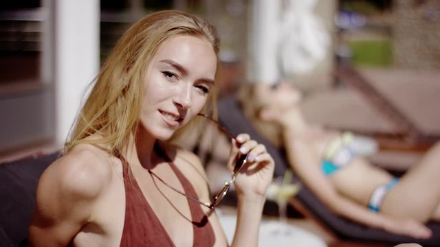 beauty in bikini lying on sun loungers and looking at camera