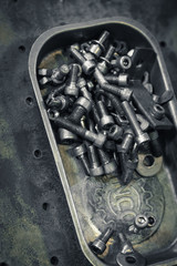 Screws and bolts in a craftsman magnetic steel tray on a metal surface