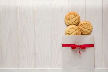 Valentine's day. Bag with cookieswith pressed text 'I love you' on white wooden background. Top view