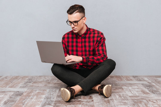 Hipster sitting on the floor with laptop - Powered by Adobe