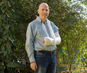 Young man with an arm cast standing in the garden