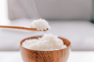 The wooden bowl is filled with rice.