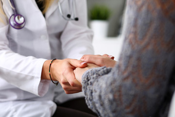Friendly female doctor hold patient hand in office during recept