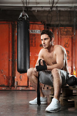 Obraz na płótnie Canvas Young strong man sitting in a gym.