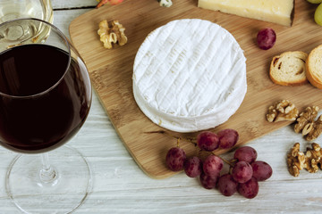 Wine, cheese, grapes and nuts on wooden board