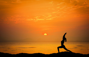 Landscapes image of Dramatic sunset over the sea with silhouette woman play yoga on the mountain.