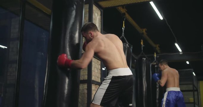 Boxers training punching bag 4k video. Fighters blows jab cross punch series, working his hands with boxing gloves in fight club.