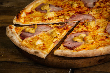 Pizza with ham and chicken on wood background