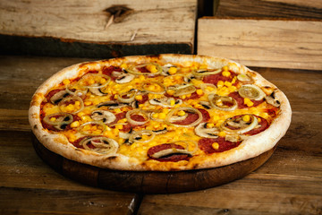 Pizza with corn, sausages and mushrooms on wood background 