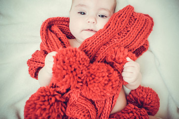 Portrait of a little girl wrapped in a large red scarf.