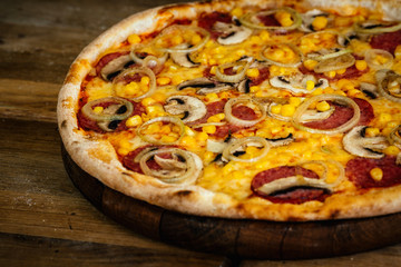 Pizza with corn, sausages and mushrooms on wood background 