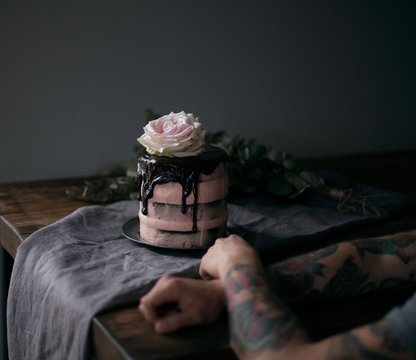 Close up of man's hand with raspberry cake in background